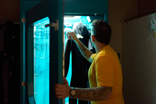 Employee sterilizing wetsuit in UV light cabinet