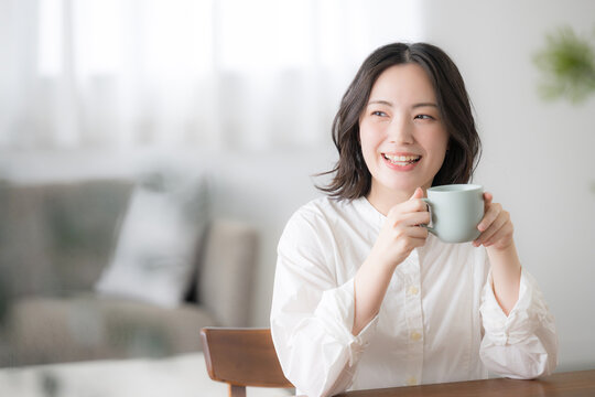 朝のくつろぐ時間にマグカップを持つ笑顔の女性ライフスタイル上半身