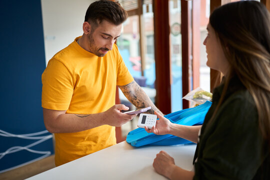 Customer making contactless payment using smartphone in dive center