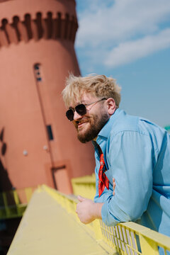 Smiling man leaning on yellow bridge railing