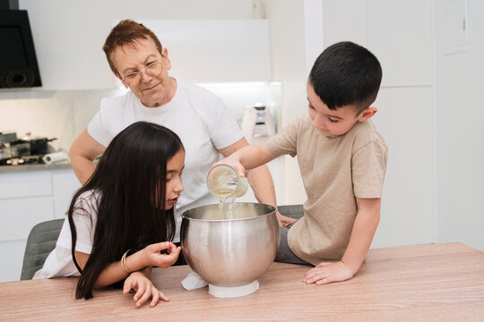 Kids and Grandmother Bake Cake Together in the Kitchen