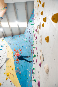 Woman rappelling down indoor climbing wall practicing bouldering