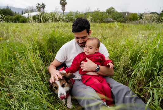 Father, son, and dog bonding in a green field