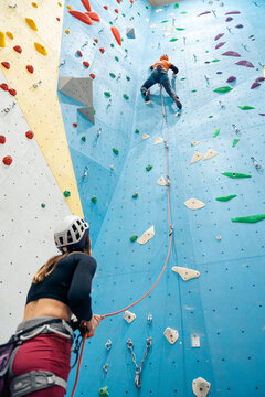 Climbers practicing lead climbing indoors with belayer