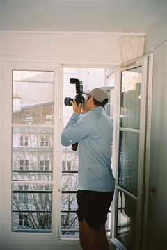 A tourist in athletic wear, taking photos from his hotel window