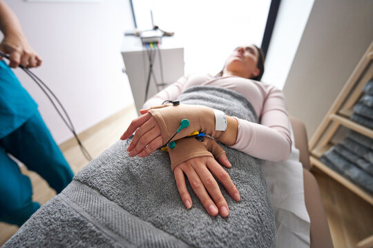 Woman receiving neurostimulation physiotherapy treatment on hands