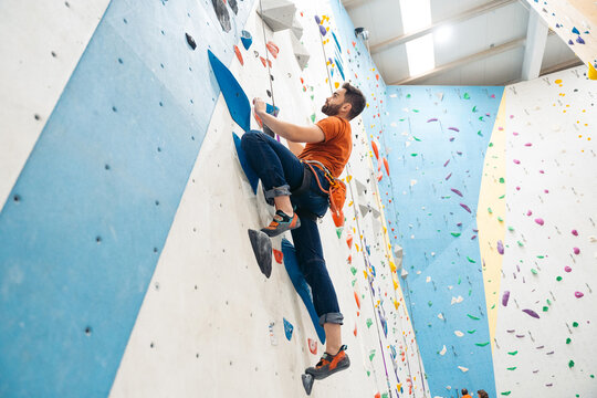 Man climbing colorful indoor rock wall at gym