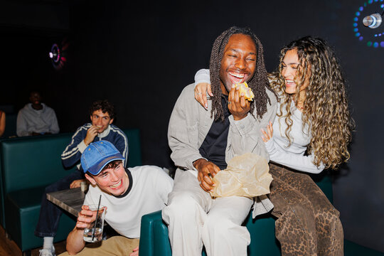 Diverse group of friends laughing and eating at night club