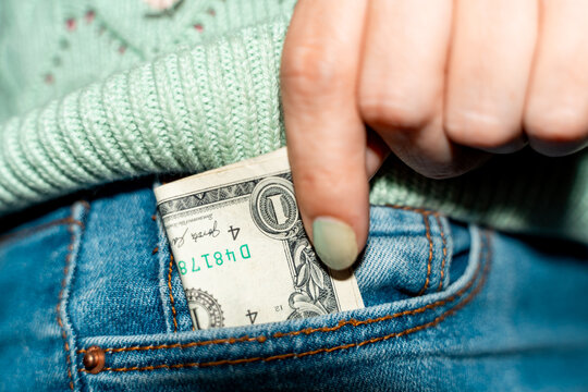 Hand Putting Dollar Bill into Denim Pocket