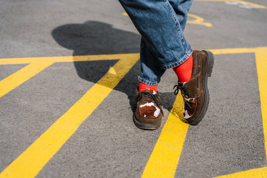 Brown shoes with red socks standing on bright yellow road
