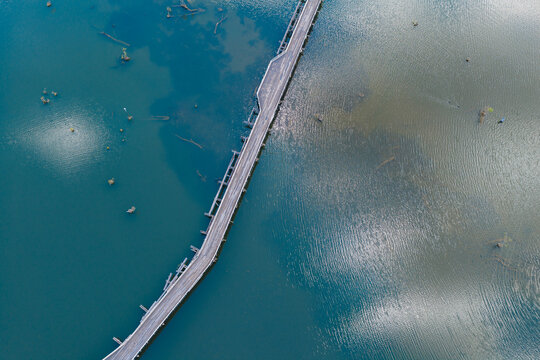 Derelict wooden bridge over sky reflections on a calm inland river