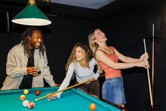 Happy friends enjoying billiards game and social time