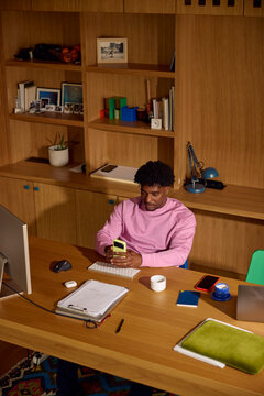 Man sends texts on his phone while at his desk