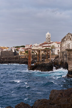 Historic Seaside Town With White Church Tower Over Rocky Coast