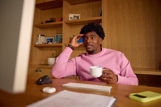 Man sitting at a desk, holding a cup of coffee