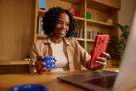 Happy woman using her phone in a home office