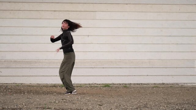 白い壁を背にダンスの練習をする女性ダンサー