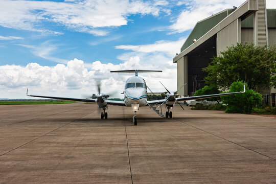 Turboprop airplane parked outside airport hangar on concrete runway tarmac