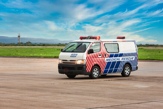 Medical rescue ambulance van driving on airport tarmac under blue sky