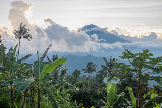 A volcano rising above clouds over lush landscape in Bali, Indonesia