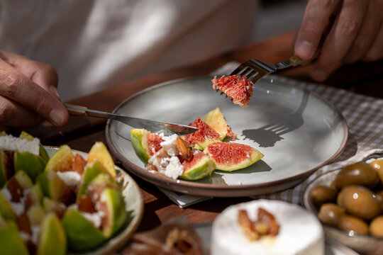 Person enjoying a gourmet appetizer of stuffed figs and prosciutto