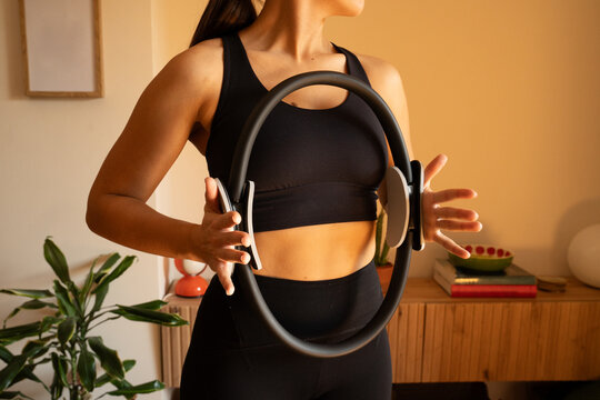 Woman exercises indoors with a fitness ring in her apartment space