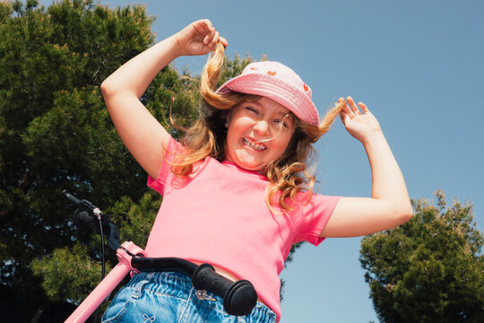Happy girl wearing bucket hat posing outdoors with scooter