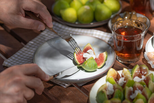 Cutting a fresh stuffed fig with knife and fork at summer lunch