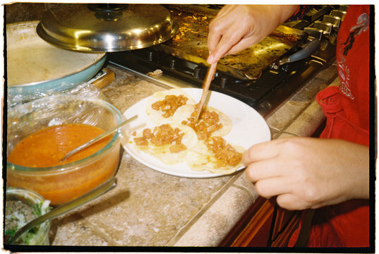 Woman Preparing Food in a Kitchen With Tortillas and Sauce