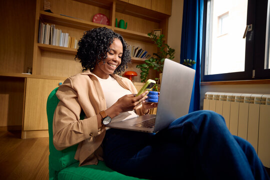 Woman sits in a green chair and uses her technical devices