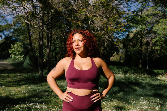 Portrait captures a smiling woman in athletic wear posing in a park