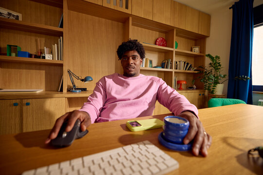Man sits back at a desk, working on a computer