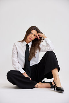 Woman in black pants and white shirt sits on floor during photo 
