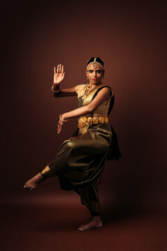 Traditional bharatanatyam dancer performing mudra on brown background