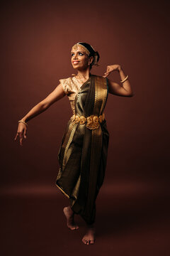 Traditional bharatanatyam dancer performing mudra on brown background