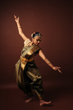 Traditional bharatanatyam dancer performing mudra on brown background