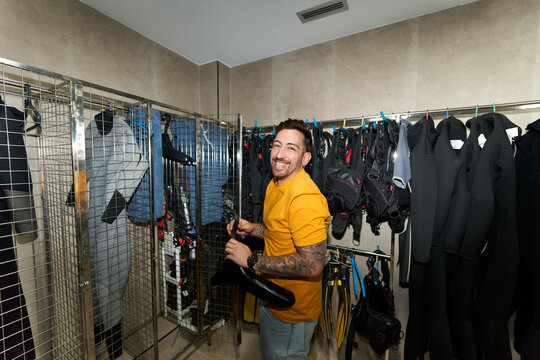 Smiling man holding scuba fins at dive center