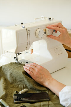 A person adjusting a sewing machine at home.