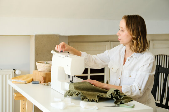 A woman adjusting a sewing machine at home.