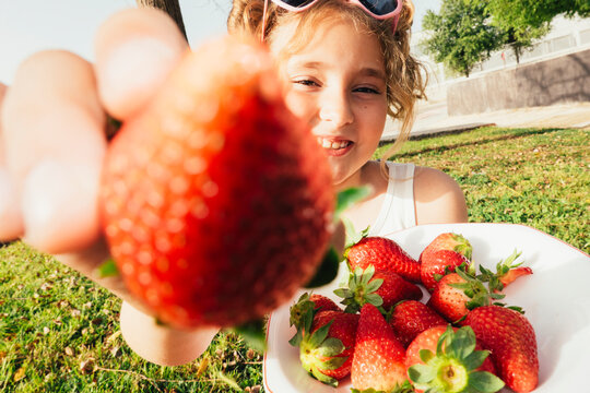 Smiling girl wearing holding strawberries outdoor very happy