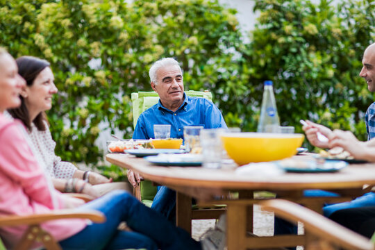 Multi-generational people enjoying family lunch outdoors in garden
