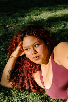 Portrait of a curvy athletic woman posing while reclining on the grass