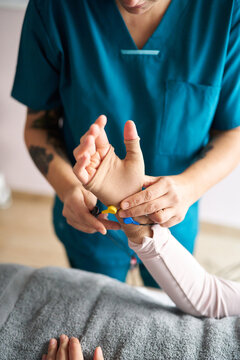 Physiotherapist using neurostimulation electrodes on patient's wrist