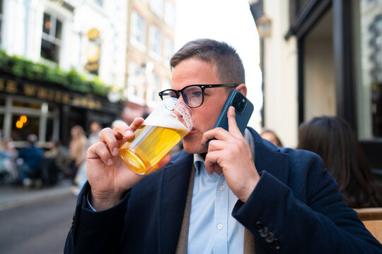 Man drinking beer while using smartphone