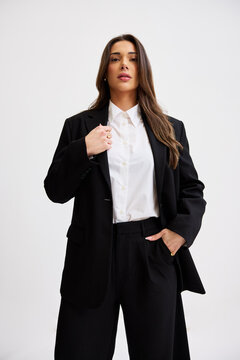 Woman in black suit standing with confidence in a studio setting