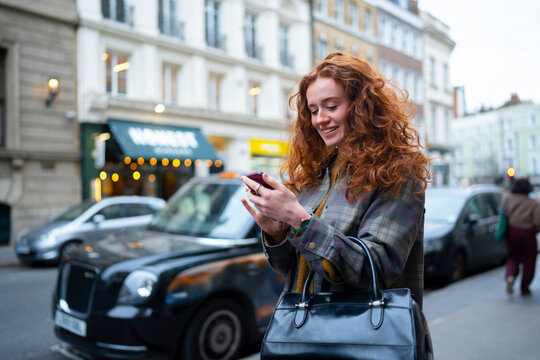 Smiling while using smartphone on London street