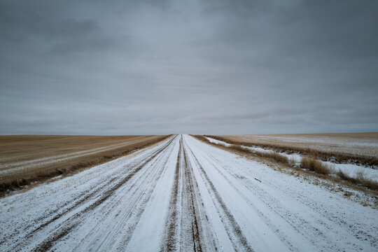 Snowy Road Stretches Into the Horizon Under a Cloudy Sky