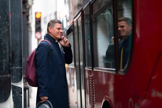 Smiling man on phone by London bus