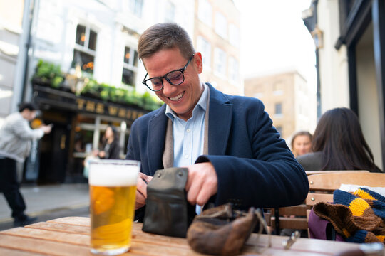 Man preparing pipe at outdoor pub table