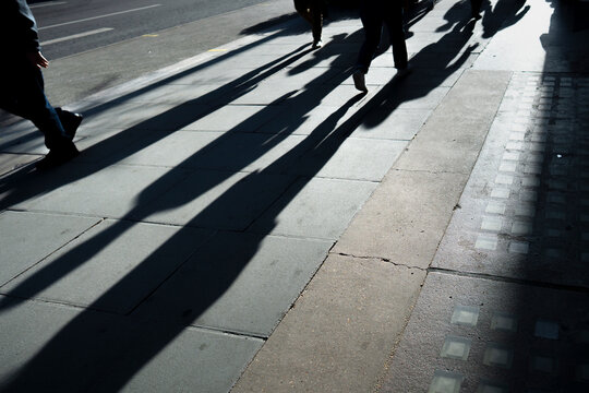 Long shadows of pedestrians on city street
